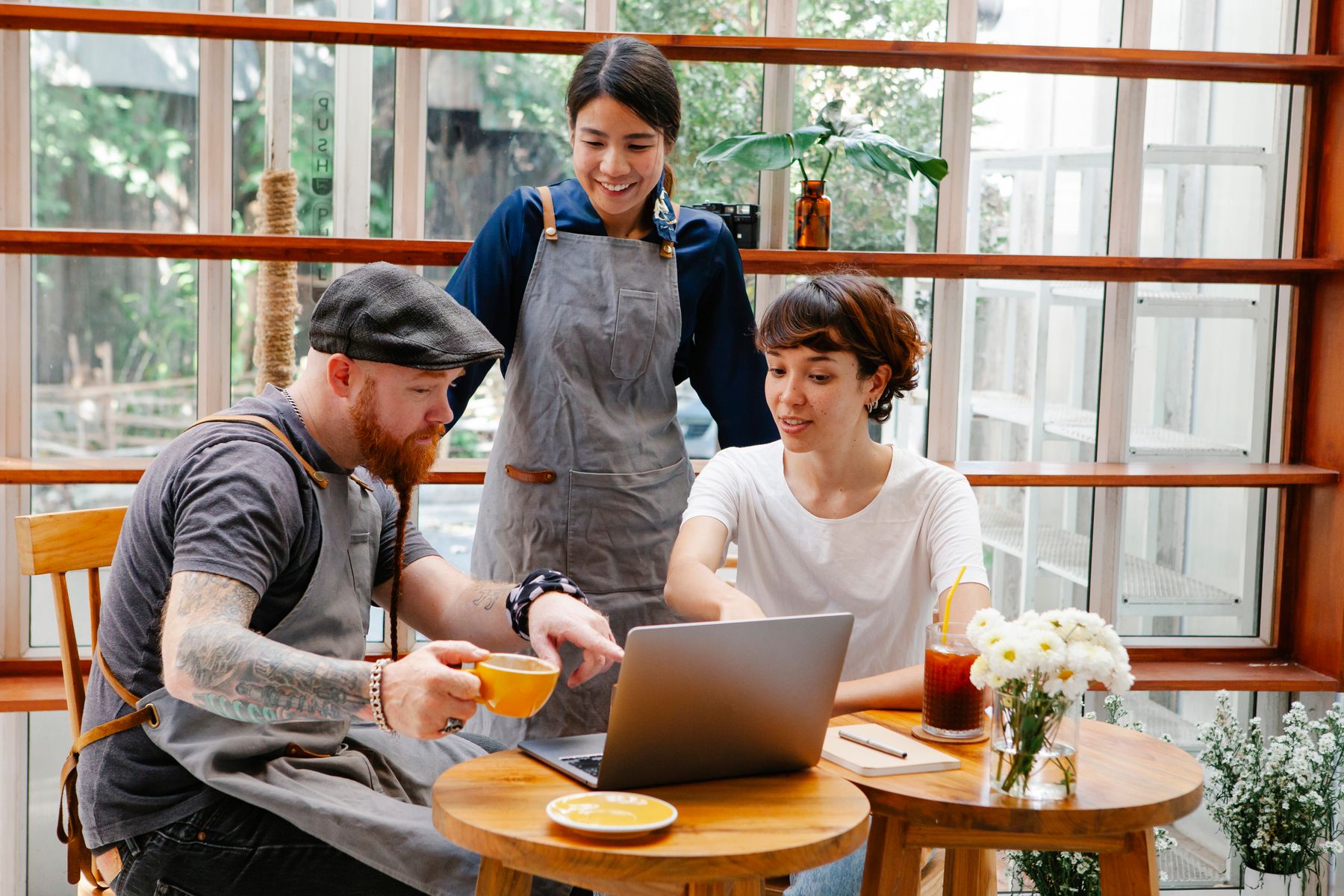 Three real café colleagues reviewing information together over coffee